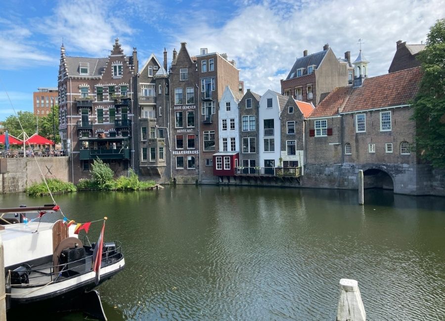 Historic canal in Delfshaven, Rotterdam, with old Dutch brick buildings reflected in the water under a blue sky