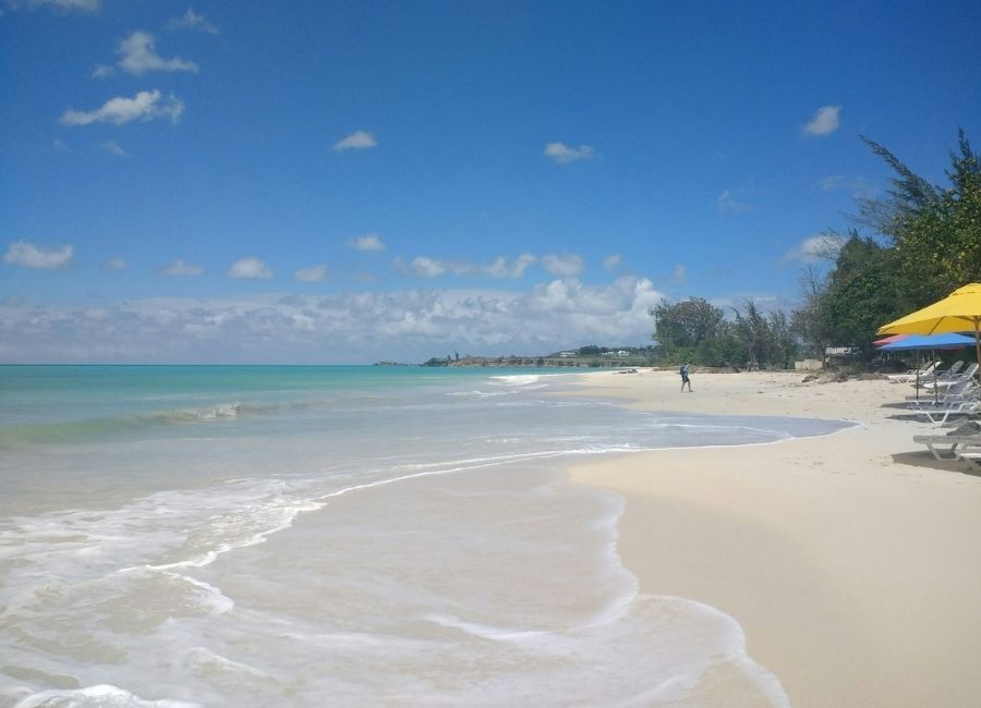 The calm turquoise water and white sand coast of Fort James Beach in Antigua and Barbuda under a clear blue sky