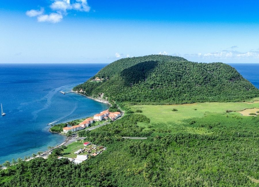 Scenic aerial coastal view of Portsmouth, Dominica, with lush green hills meeting the deep blue Caribbean Sea