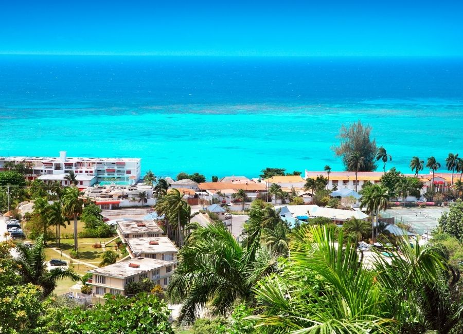 Aerial view of Montego Bay, Jamaica, showing the turquoise Caribbean Sea, palm trees, and coastal resorts.