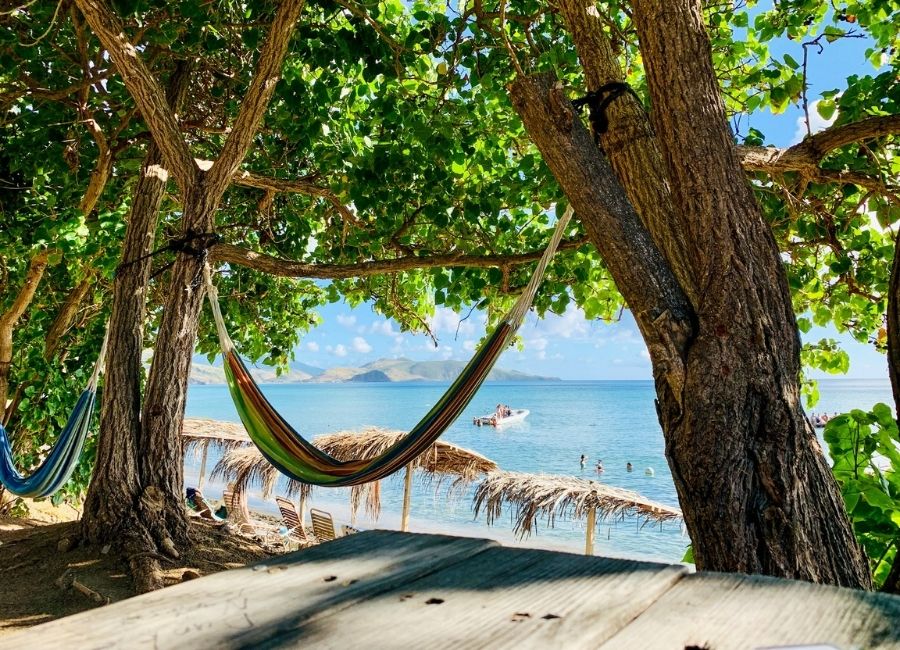 Hammocks hanging between trees at the Shipwreck Beach Bar and Grill in Saint Kitts, overlooking the sea