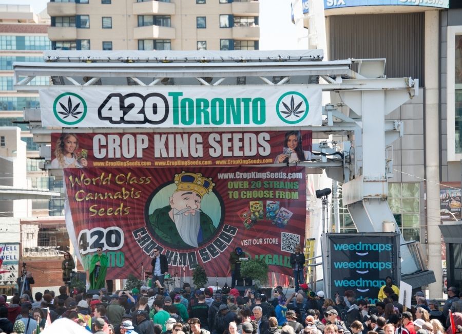 A crowd celebrating the 2016 420 Toronto cannabis festival with banners promoting local cannabis brands