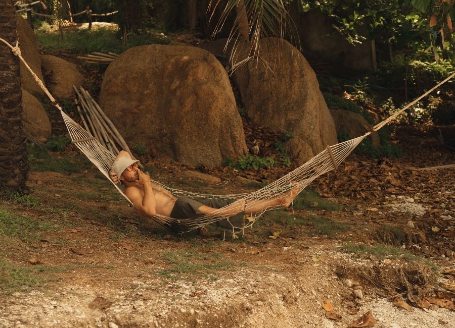 A Man relaxing in a hammock and smoking cannabis under the palm trees