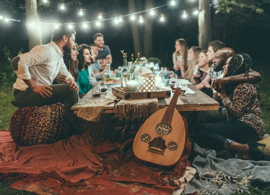 Group sharing a communal outdoor dinner at a retreat-style gathering in the evening