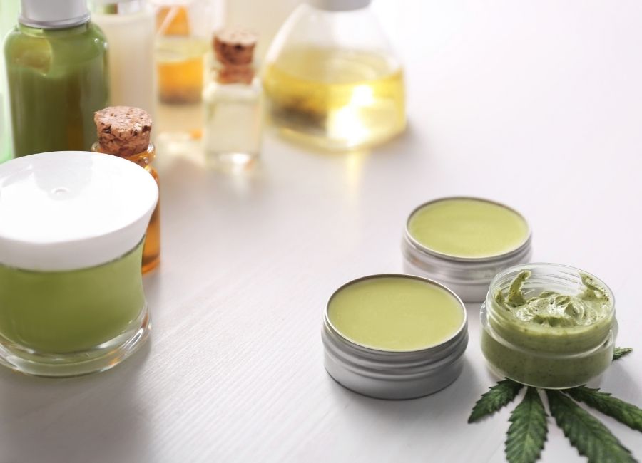Cannabis topical creams and oils displayed in small jars and bottles on a light background