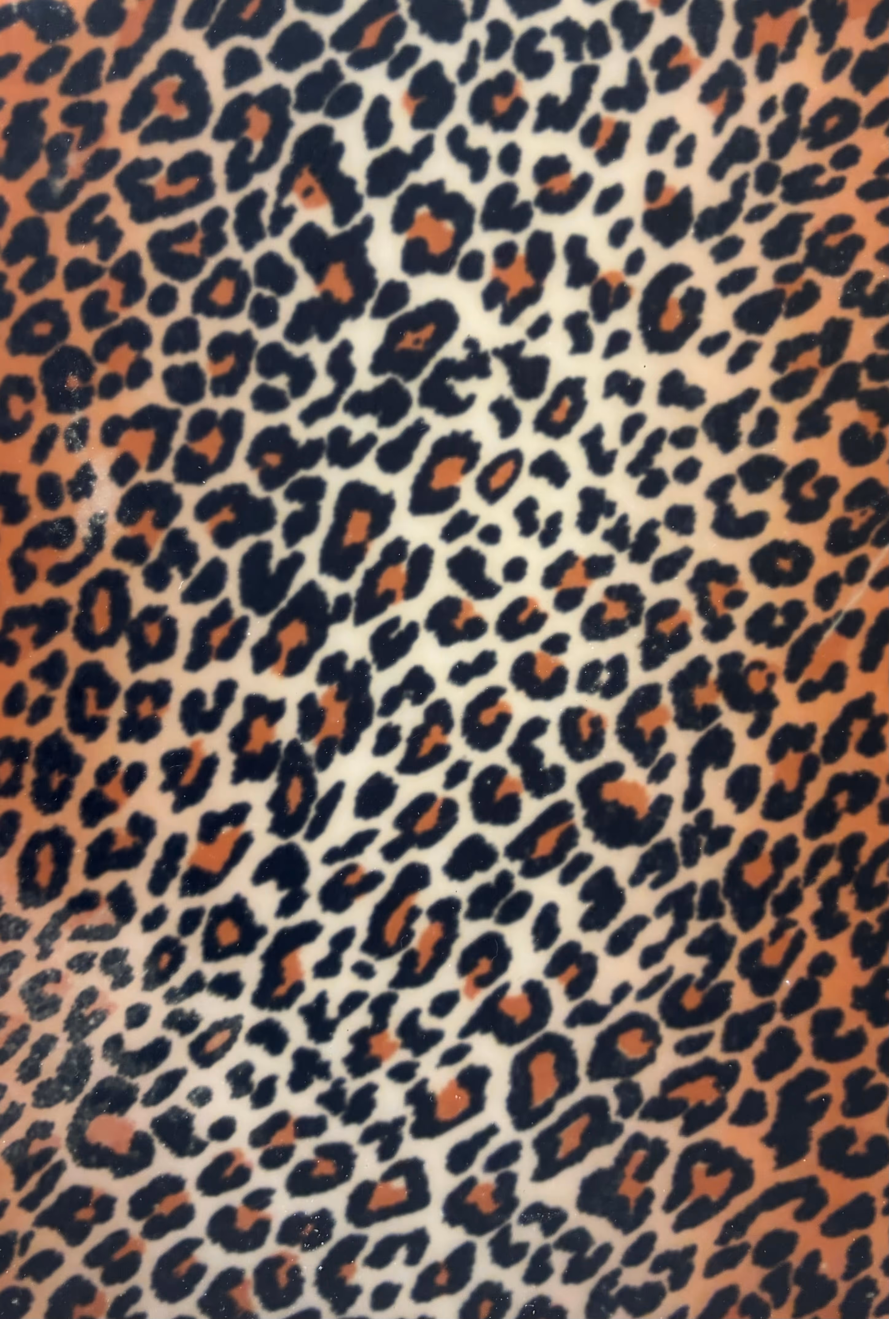 Motif léopard noir, brun et crème sur un fond imitant la fourrure.