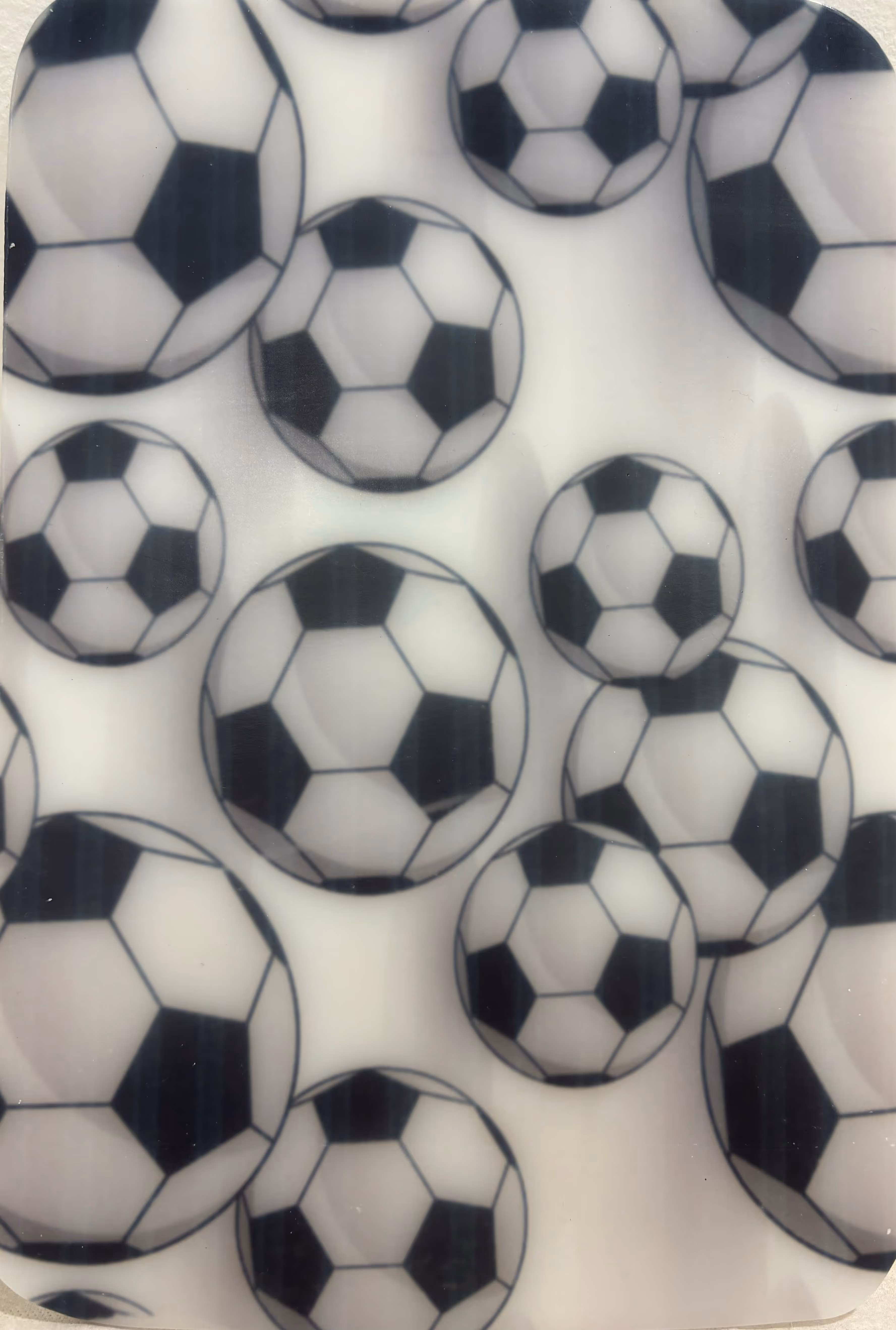 Multiple black and white soccer balls arranged closely on a light background.