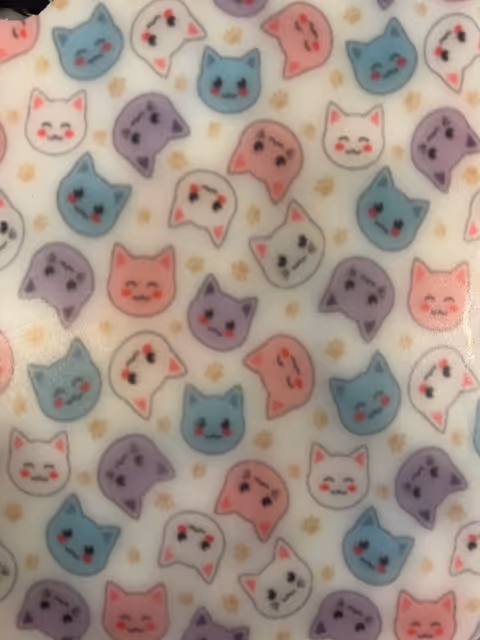 Motif de visages de chats colorés souriants en rose, bleu, violet et blanc sur fond clair.