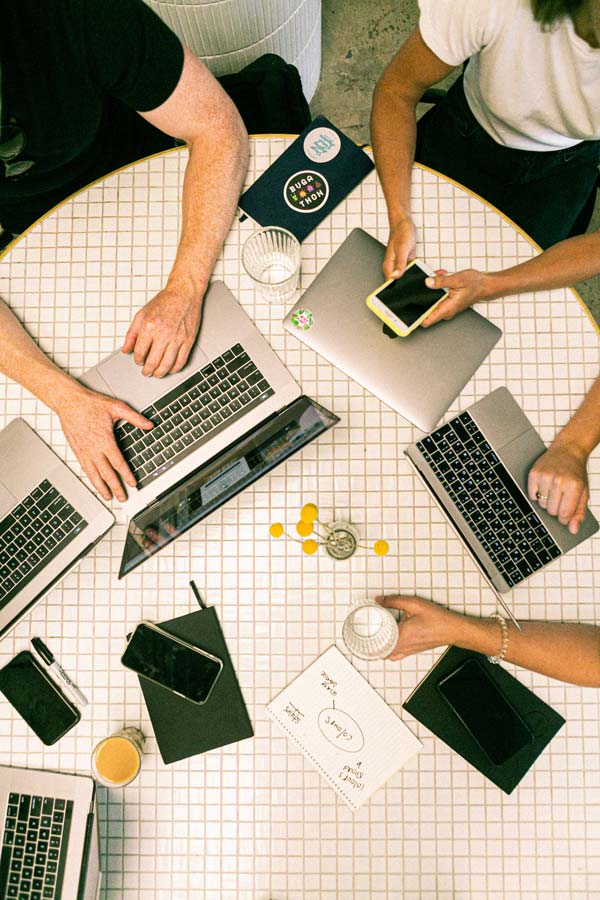 A team of creatives huddles around a table with their smart devices.