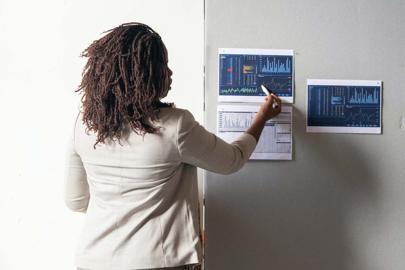 Woman points to data printed out and posted on the wall.