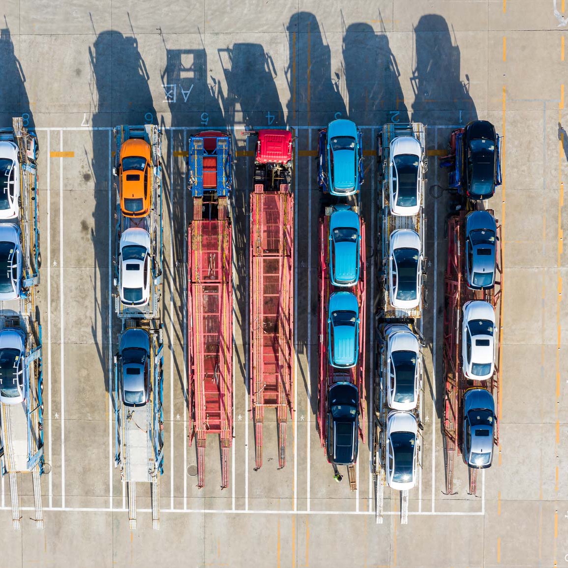 Aerial view of a loading lot with vehicles loaded on transport carriers.
