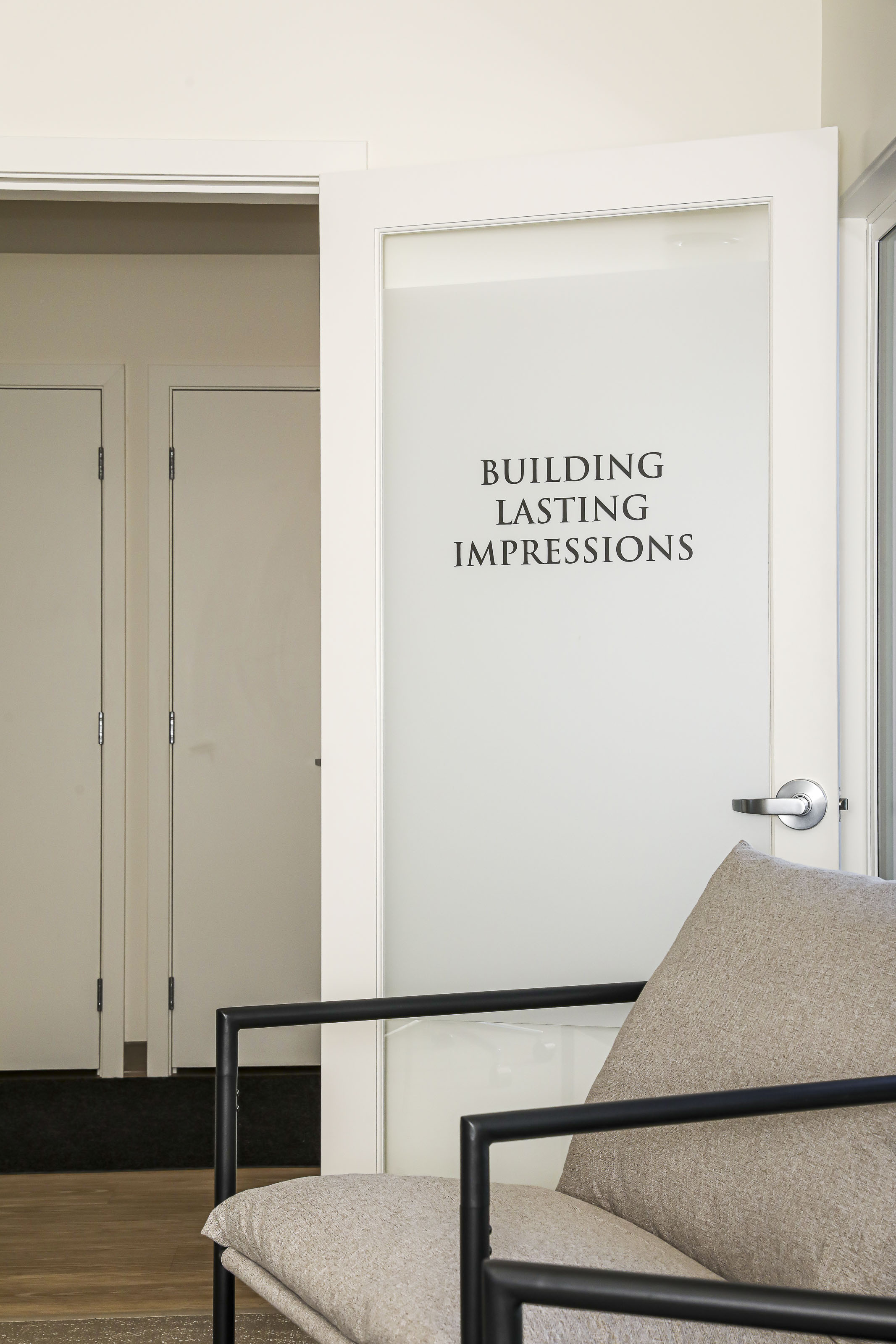 Office entrance at Outlook Project Management with the phrase “Building Lasting Impressions” printed on a frosted glass door, reflecting the company’s client-focused philosophy.