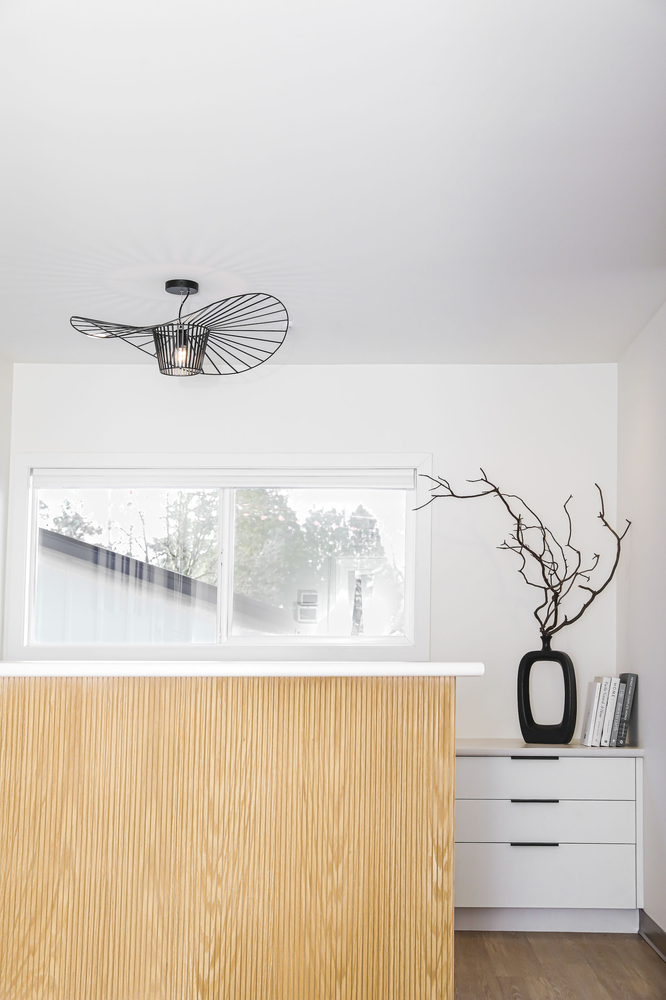 Reception area at Outlook Project Management’s office, featuring a textured wood reception desk, sculptural ceiling light, and curated minimalist decor.