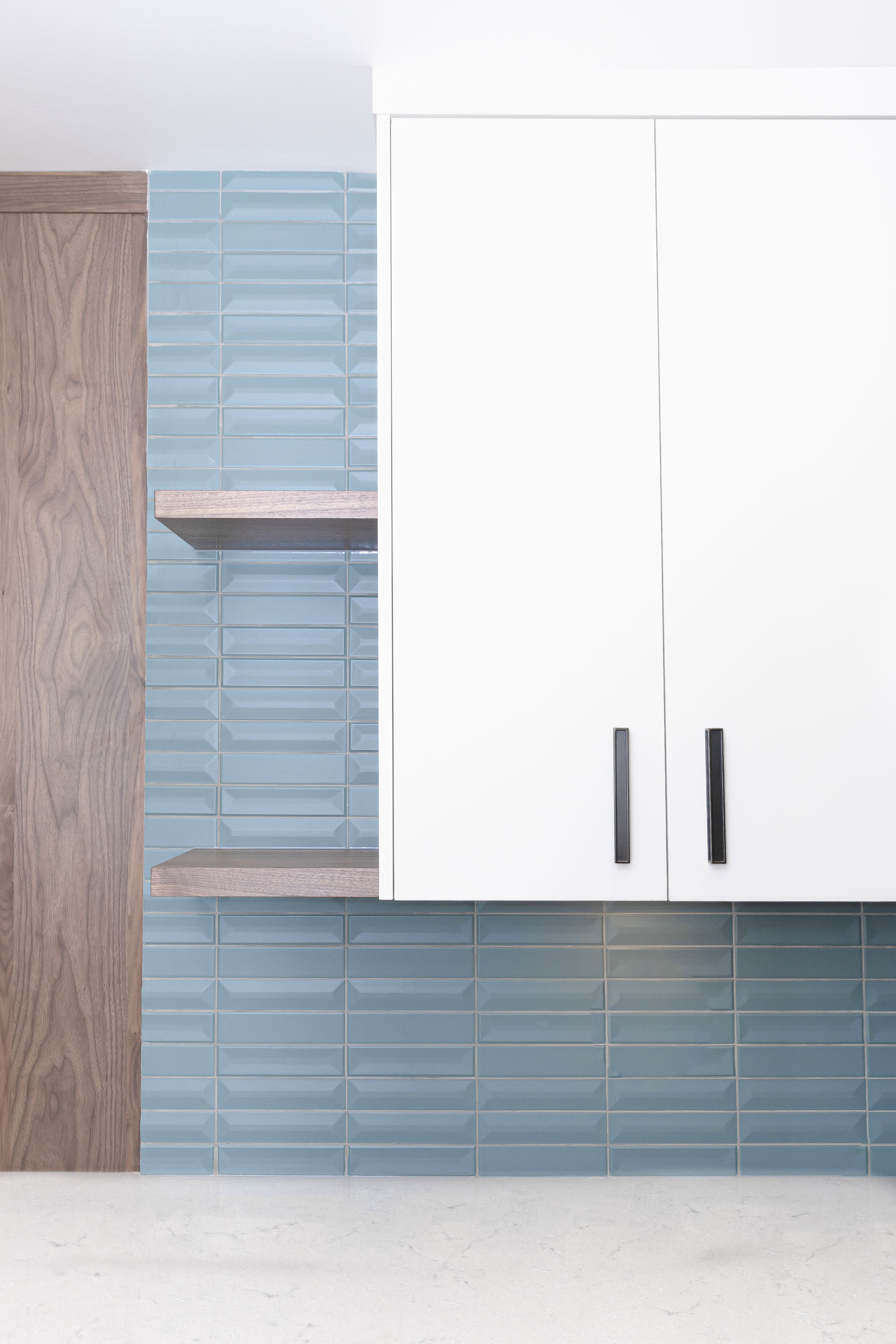 Built-in white window seat with storage drawers, open shelving, and a large picture window showcasing a tree with autumn leaves.