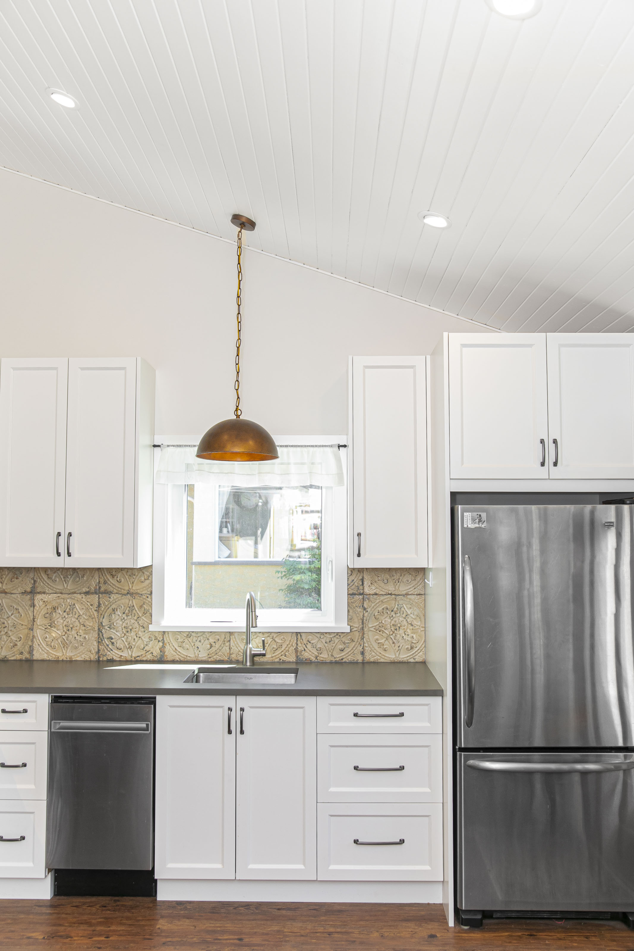 Exterior view of a newly built carriage house in Victoria, BC with stucco siding, yellow trim, and gabled roof design