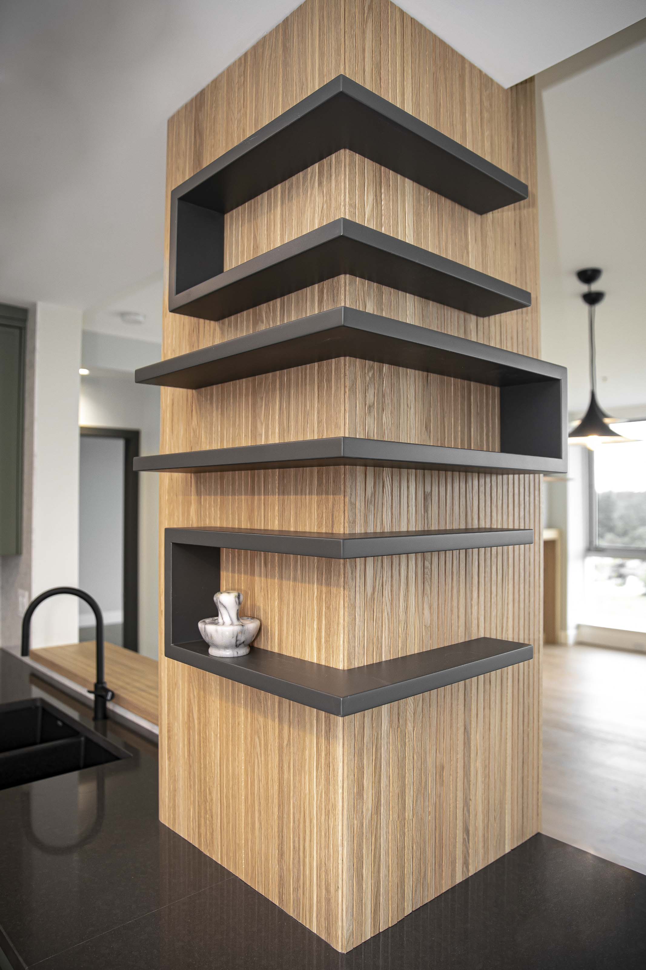 Modern kitchen shelving wrapped in vertical tambour paneling with matte black open shelves, part of Outlook Project Management’s full home remodel in Victoria, BC