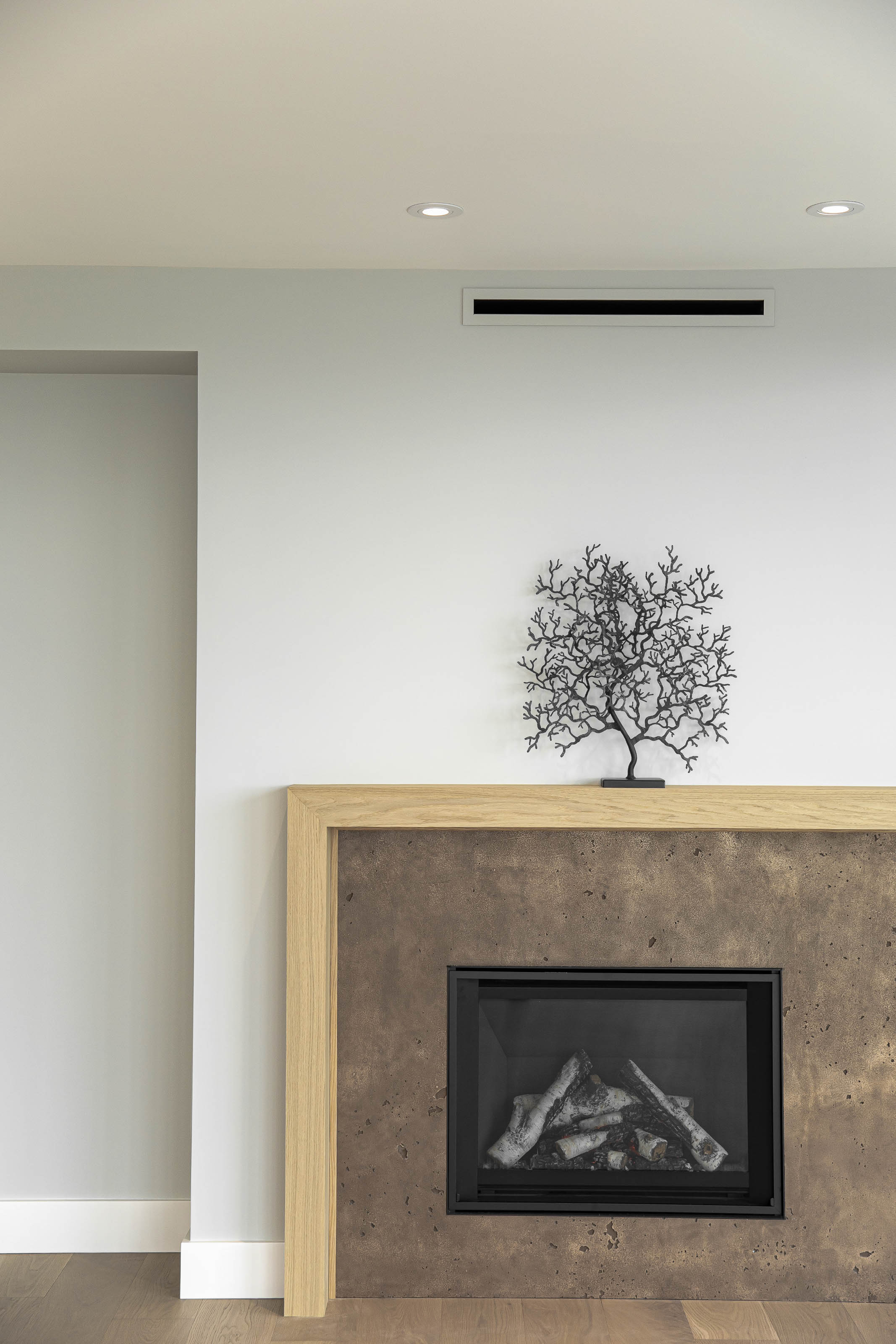 Contemporary gas fireplace with textured stone surround and natural wood frame, custom millwork by Outlook Project Management in Victoria, BC