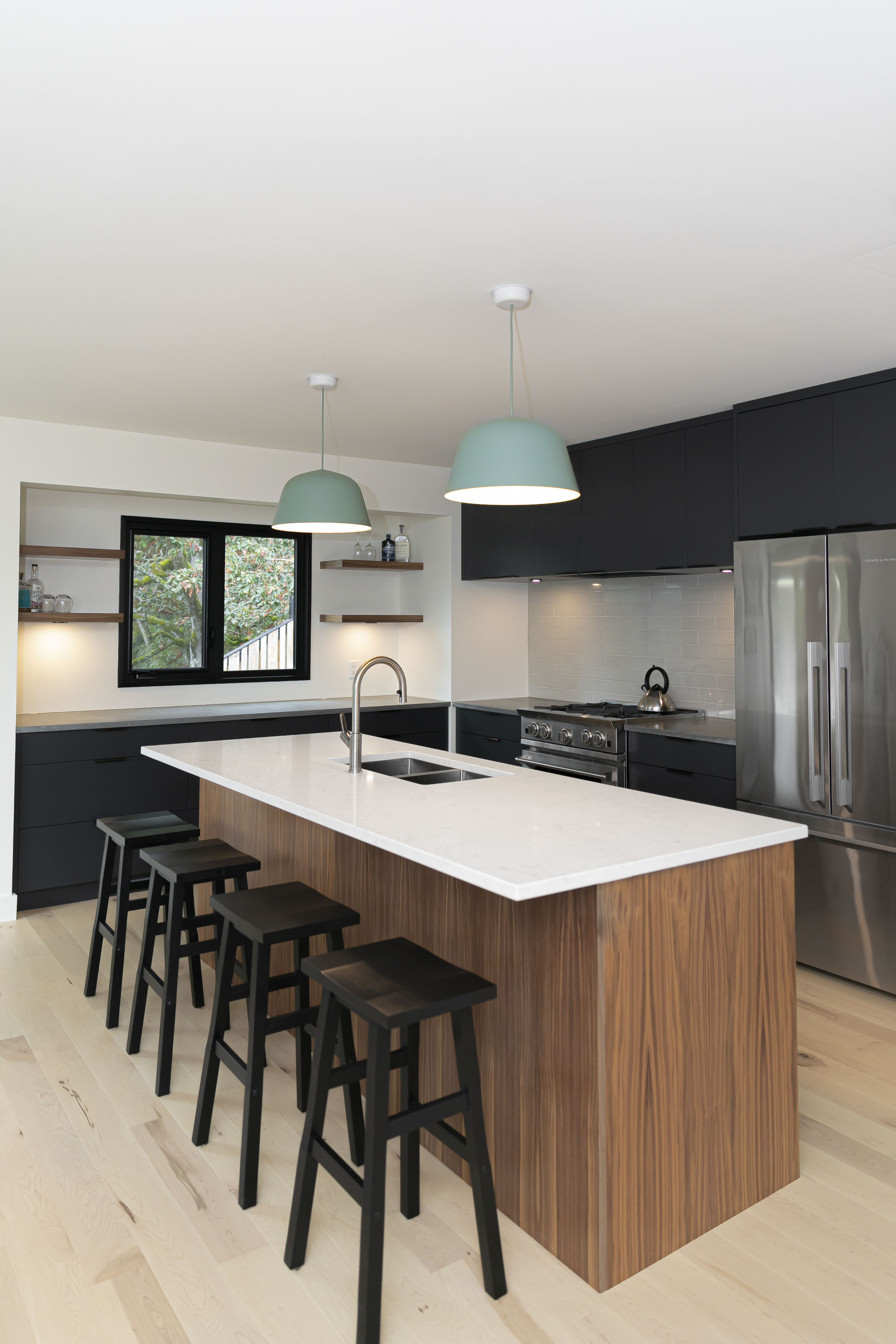 Kitchen island with waterfall quartz countertop and black bar stools in the Warder Home Renovation by Outlook Project Management in Victoria BC