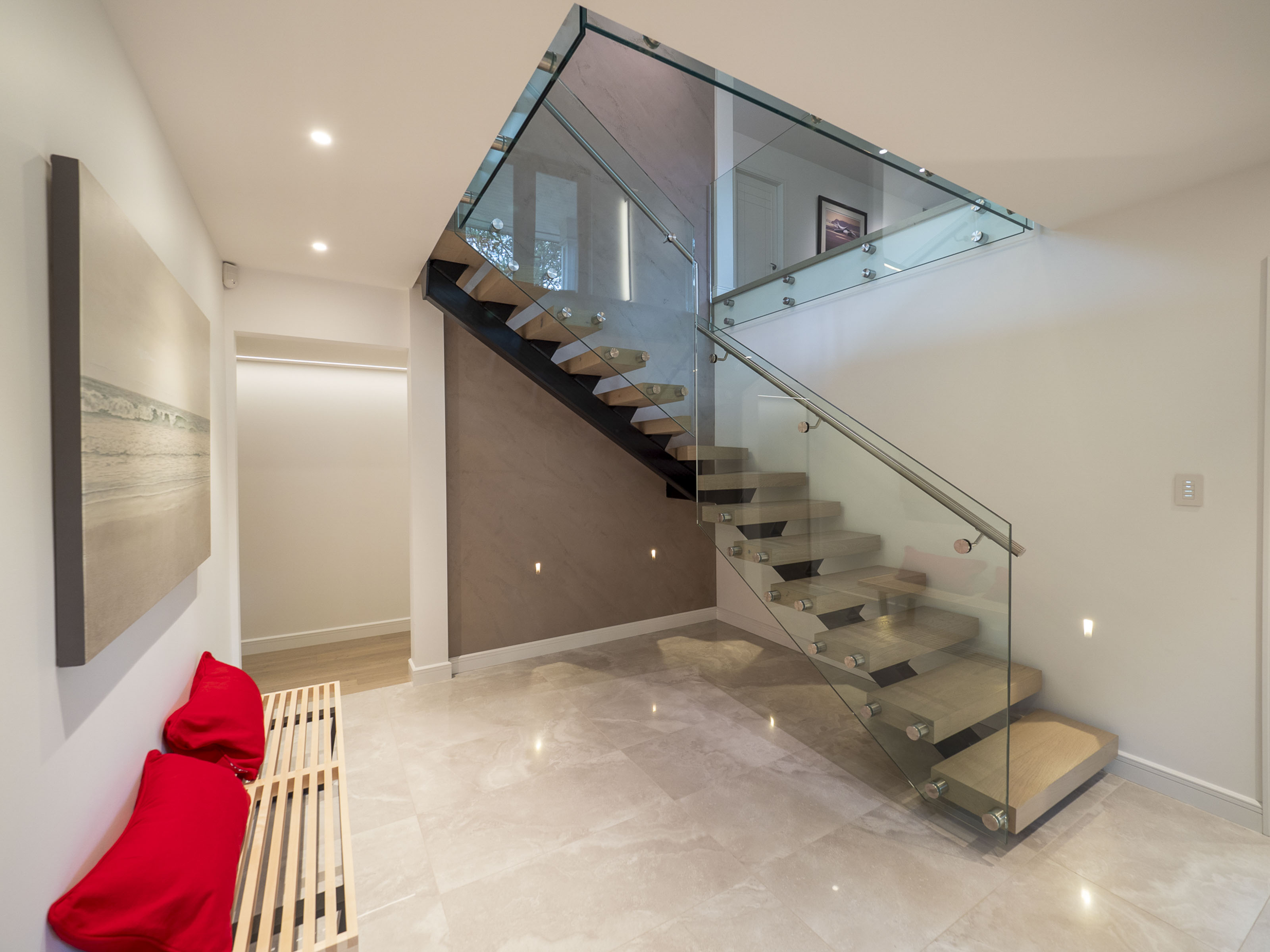 Modern custom staircase renovation by Outlook Project Management Victoria BC - Delmonte project featuring floating hardwood treads, stainless steel and glass railings, polished marble floors, and contemporary interior design