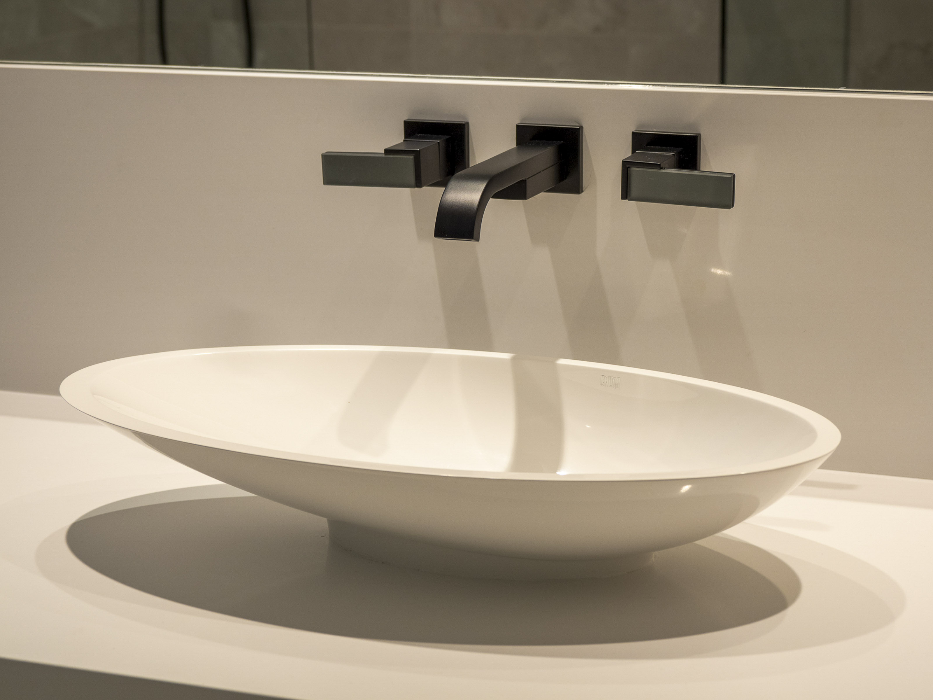 Modern bathroom sink installation Victoria BC - white vessel sink with wall-mounted black faucet and marble countertop by Outlook Project Management Delmonte project