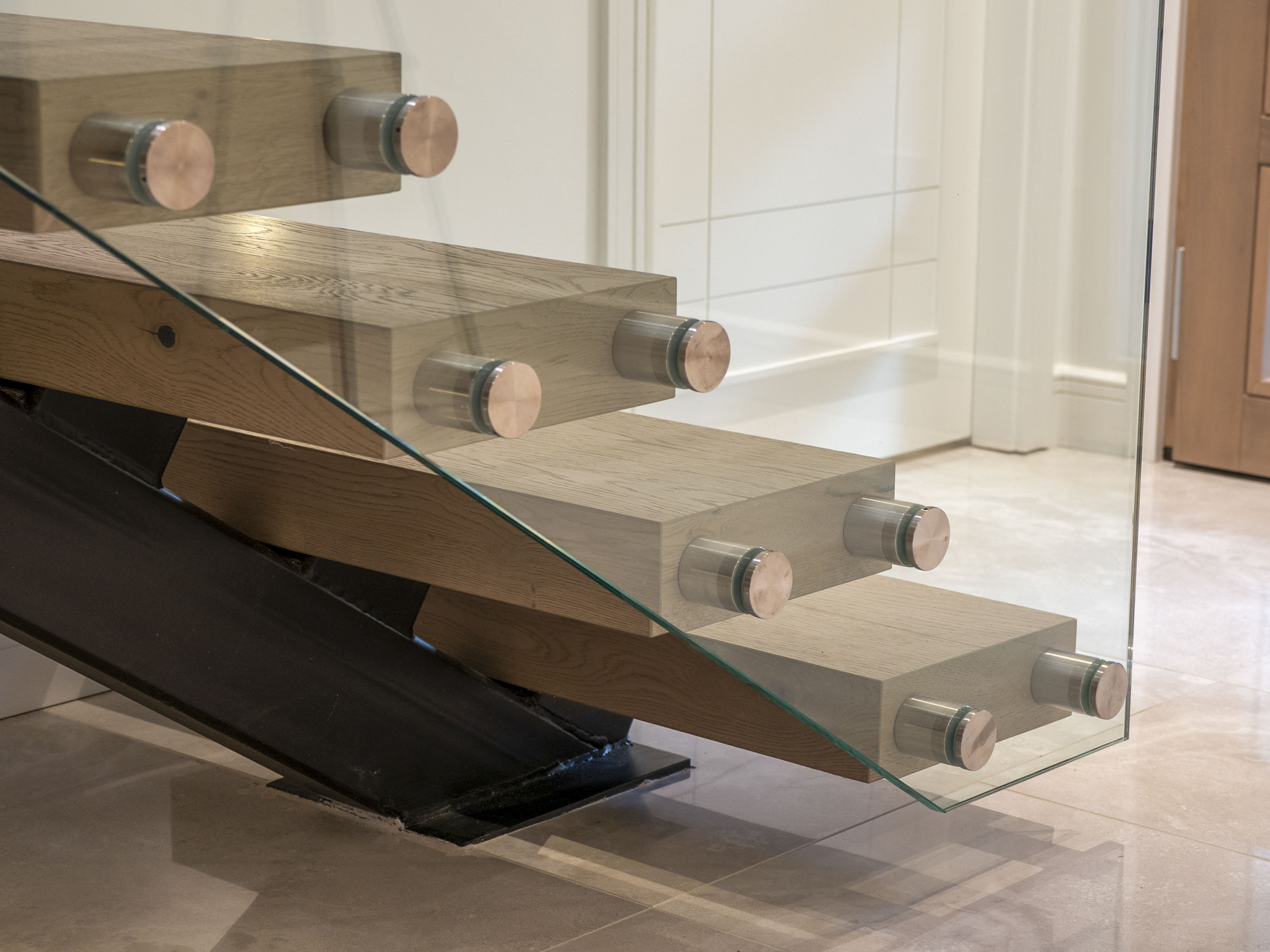 Modern custom staircase renovation by Outlook Project Management Victoria BC - Delmonte project featuring floating hardwood treads, stainless steel and glass railings, polished marble floors, and contemporary interior design