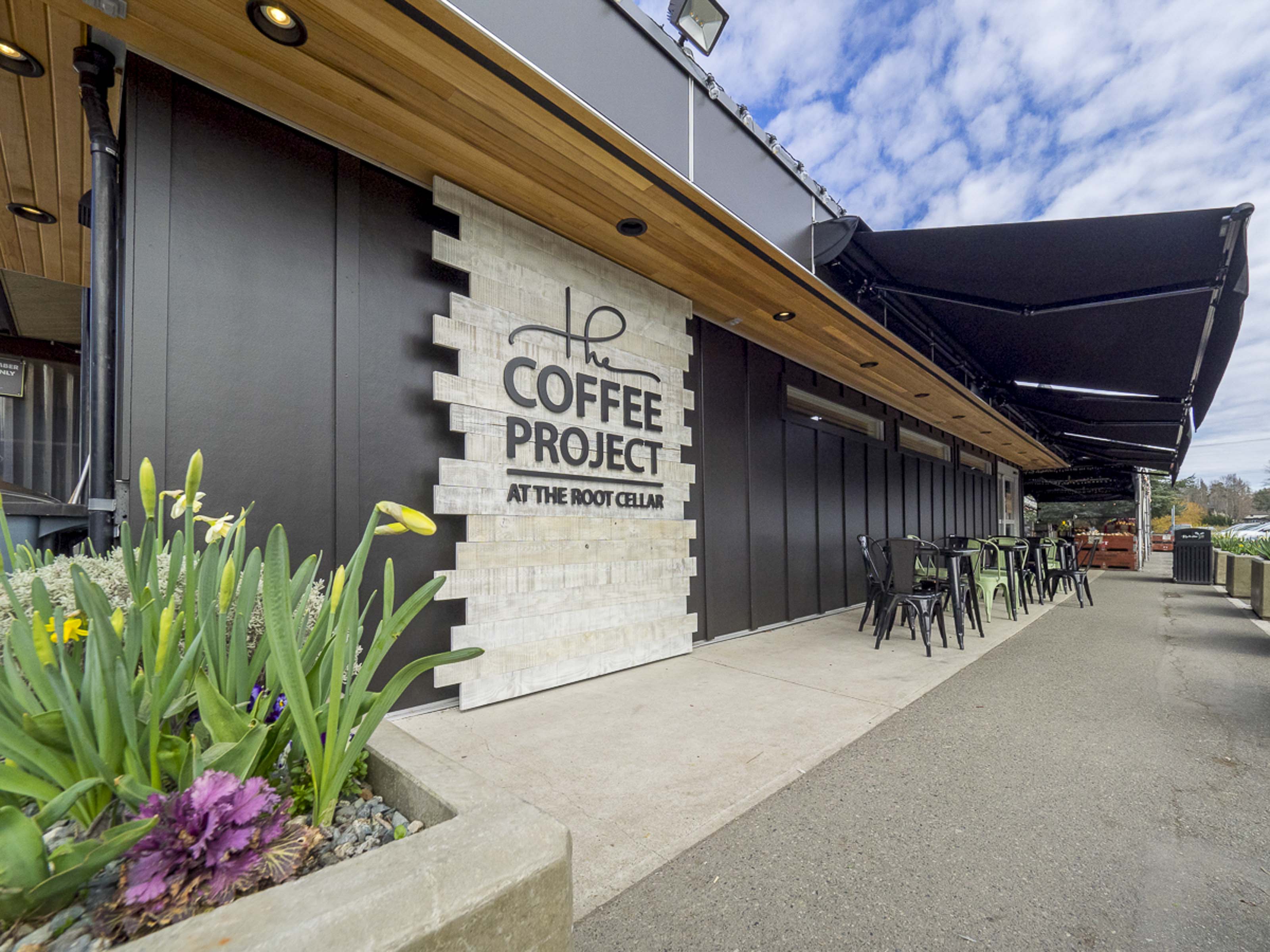 Modern coffee shop exterior construction Victoria BC - Outlook Project Management Coffee Project tenant improvement featuring contemporary signage, outdoor patio, wooden ceiling design, and commercial restaurant build-out