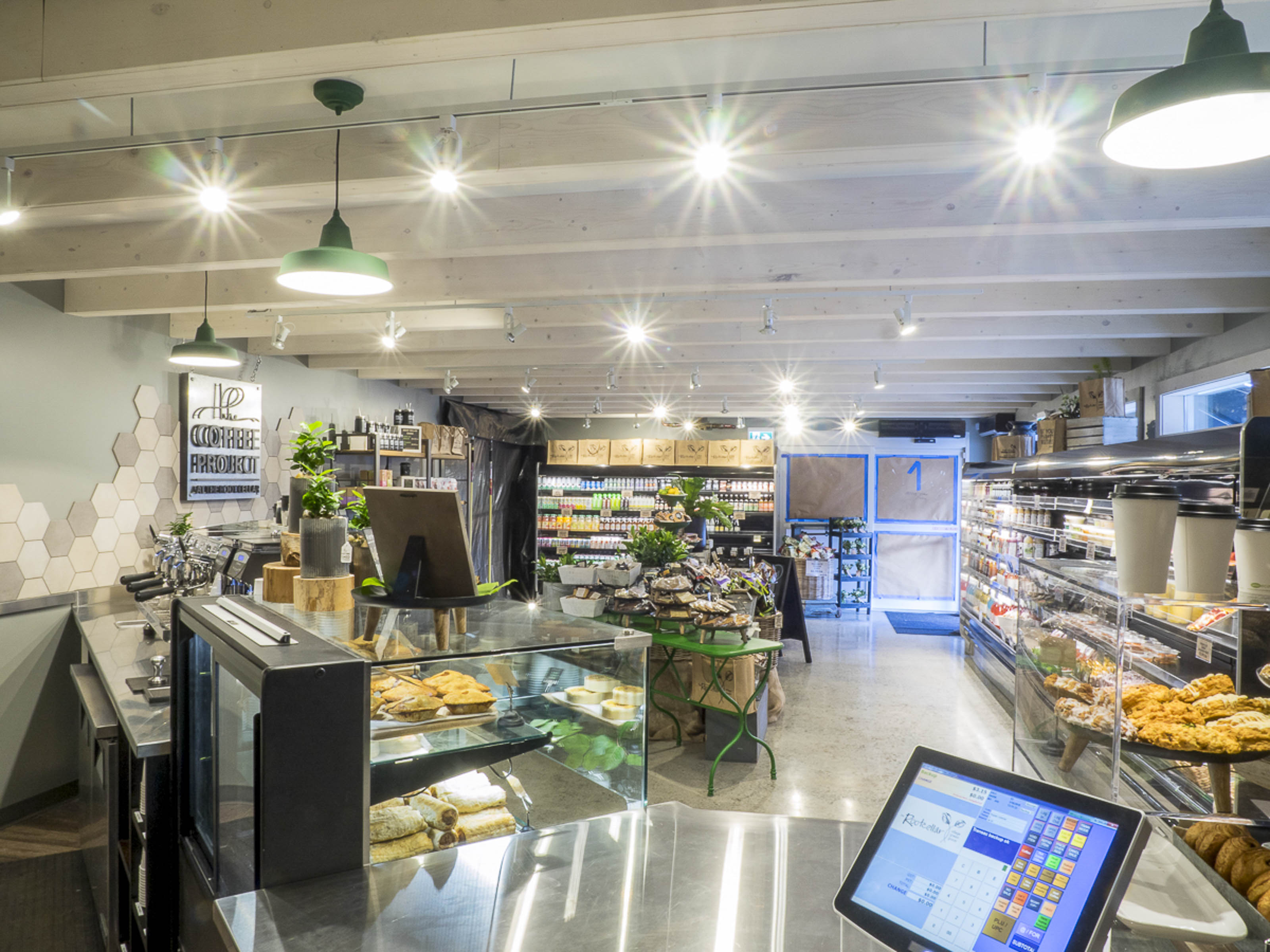 Complete coffee shop renovation Victoria BC - Outlook Project Management Coffee Project showing transformed shell space with modern lighting, exposed ceiling, and full commercial cafe build-out