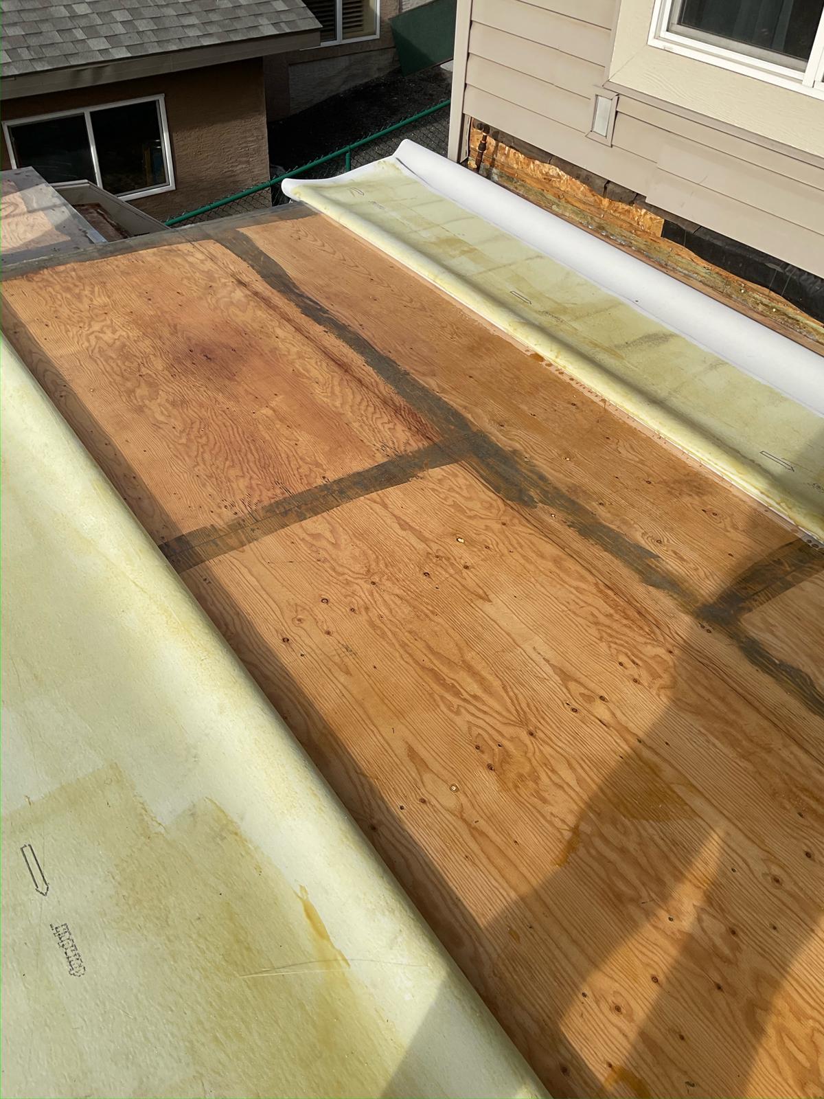 A plywood deck surface with two sheets of Duradek in the process of being glued down.