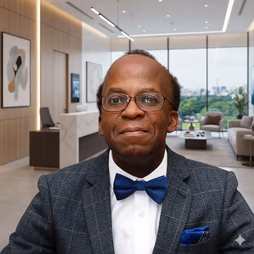 Smiling male doctor wearing glasses and a blue bow tie in a modern clinic office.