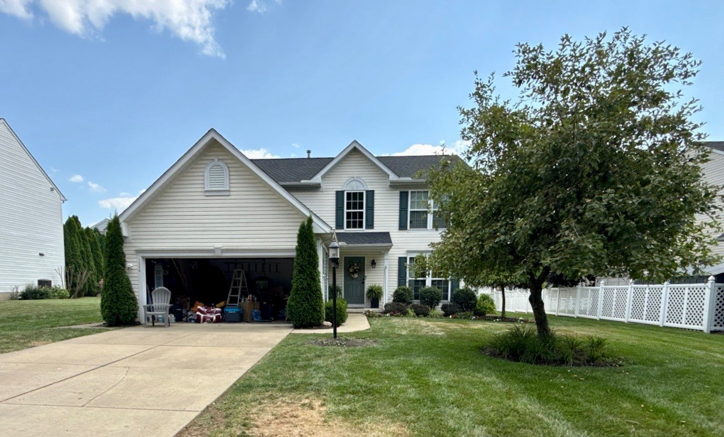 A two-story house with a garage, surrounded by a well-maintained lawn and trees.