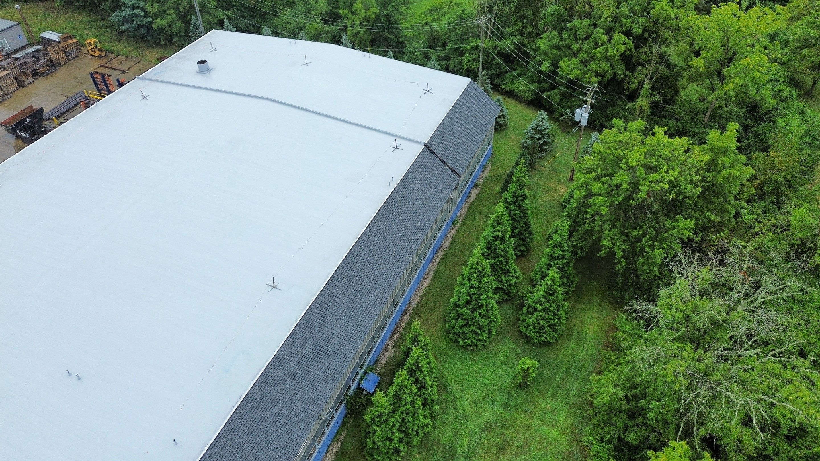 Aerial view of a large gray building surrounded by greenery and small trees.