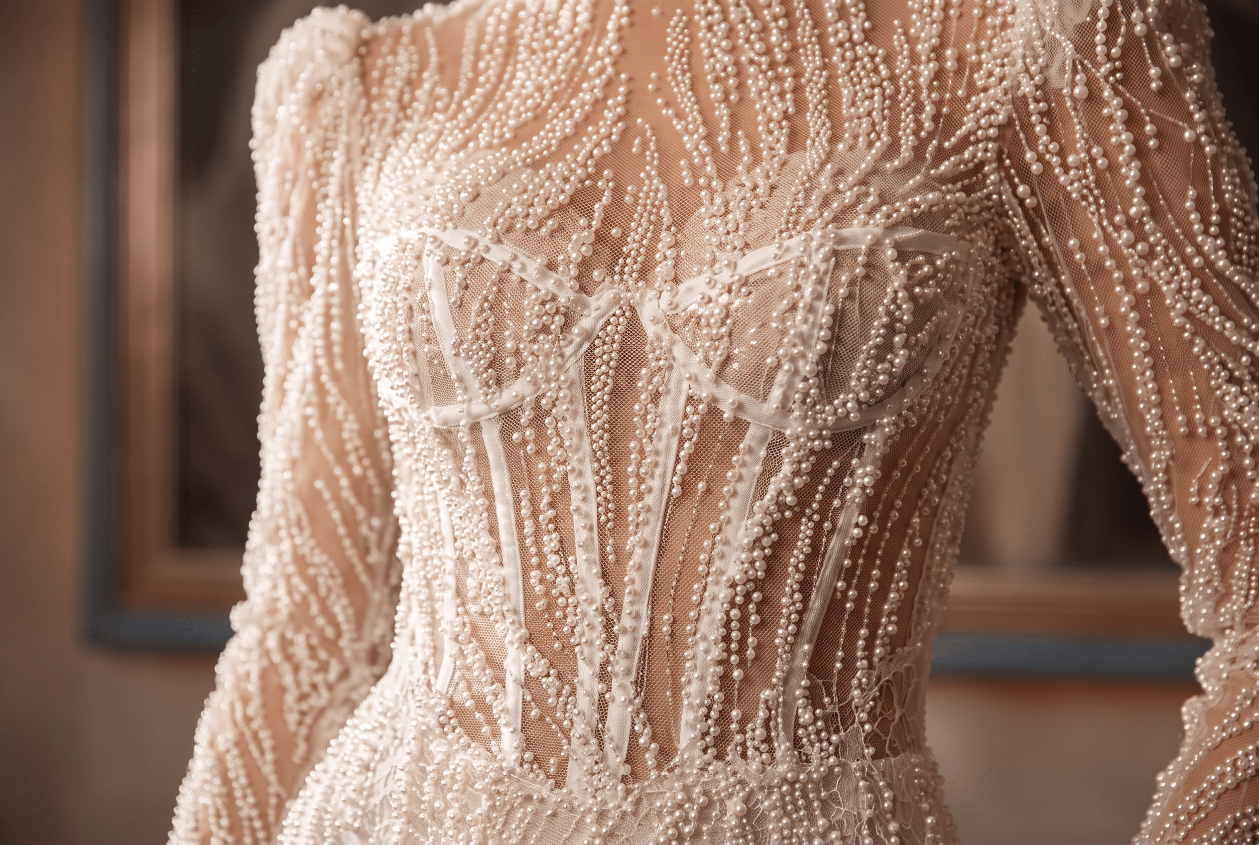 Close-up of a sheer beige dress adorned with intricate pearl bead embroidery.