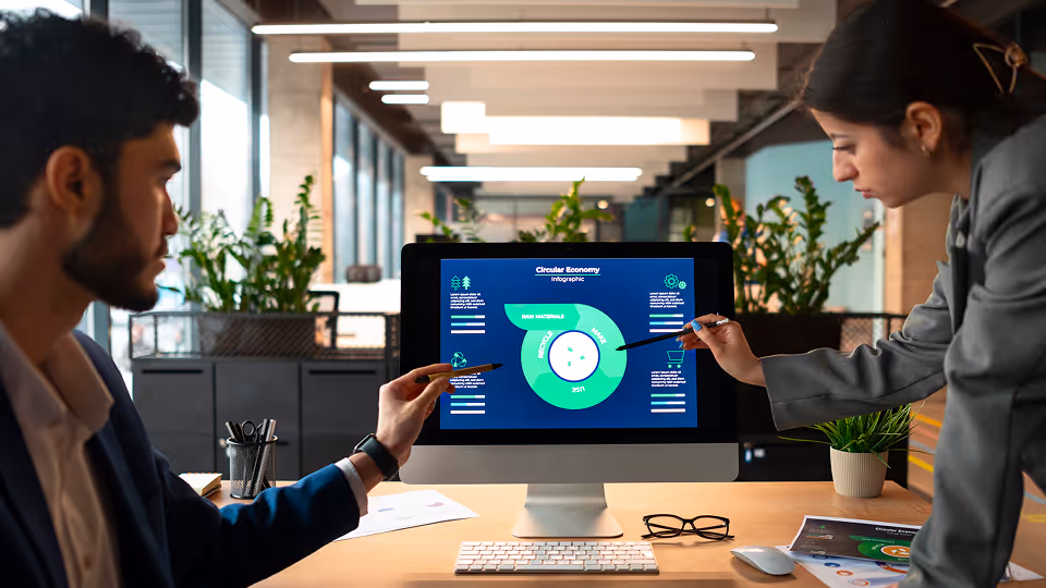 Two people working together on a computer in an office.