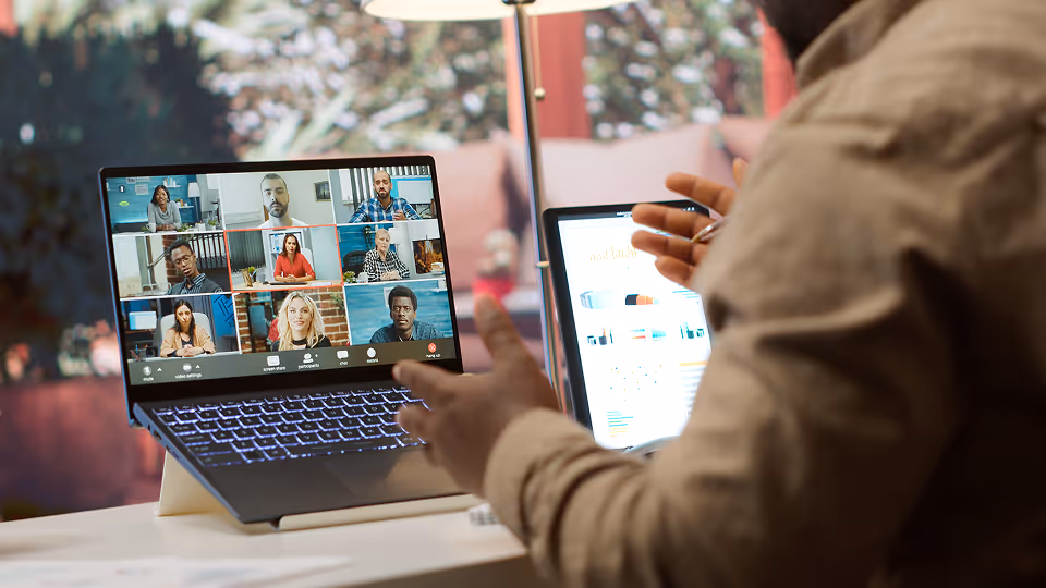 An employee is sitting at their desk and having a meeting on their laptop