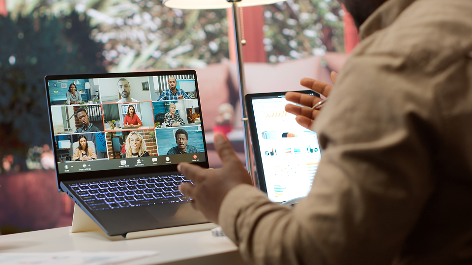 An employee is sitting at their desk and having a meeting on their laptop