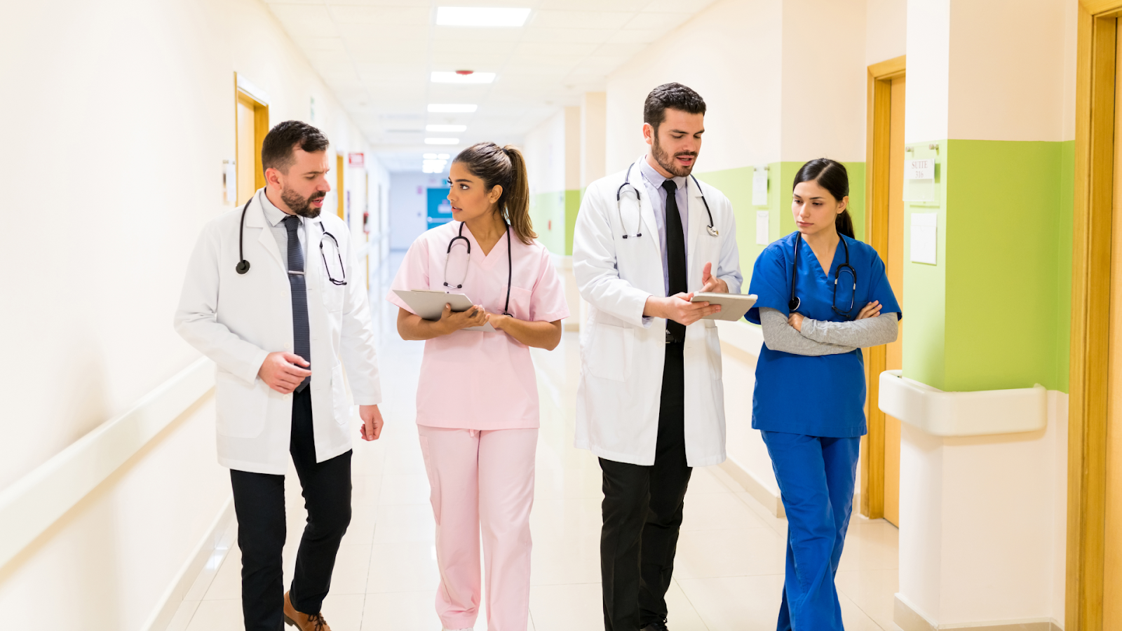 A team of doctors and nurses in a hospital reviewing information on a tablet and clipboard.