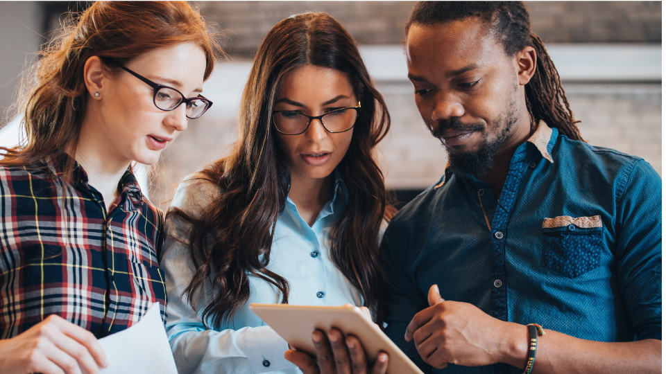 Three people looking at a tablet in an office.