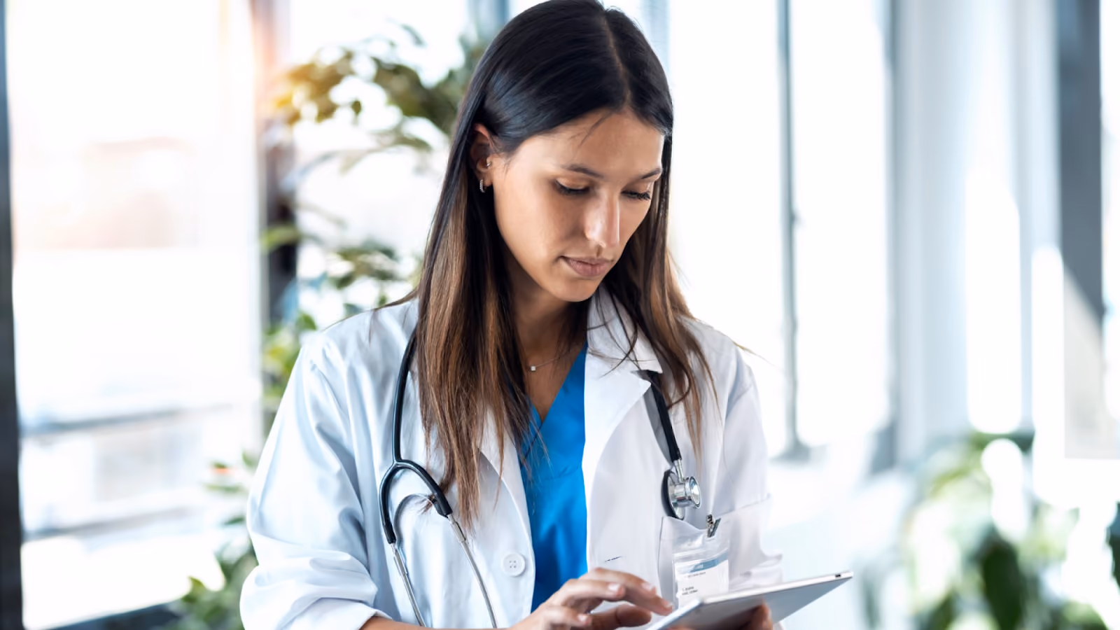 A doctor checks staffing levels and overtime alerts on a tablet during a busy hospital shift to catch overtime risk early.
