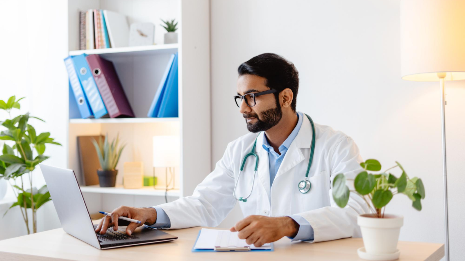 A doctor reviews employee absence data on a laptop to support the employee absence management process.