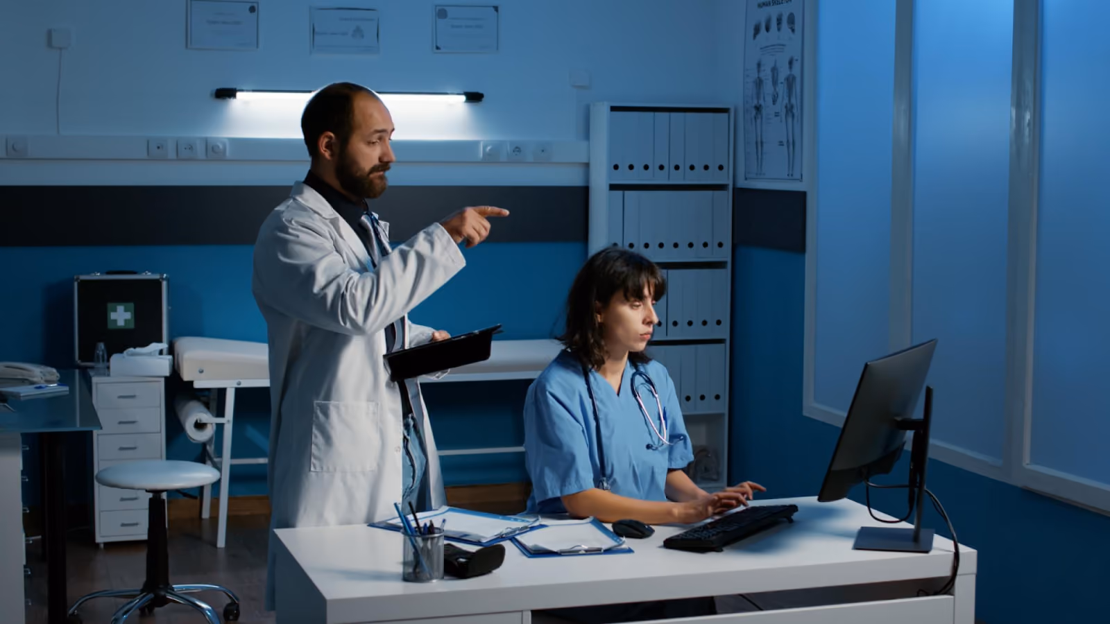 A doctor points toward a computer as a nurse works, highlighting the impact of employee absences on staff.