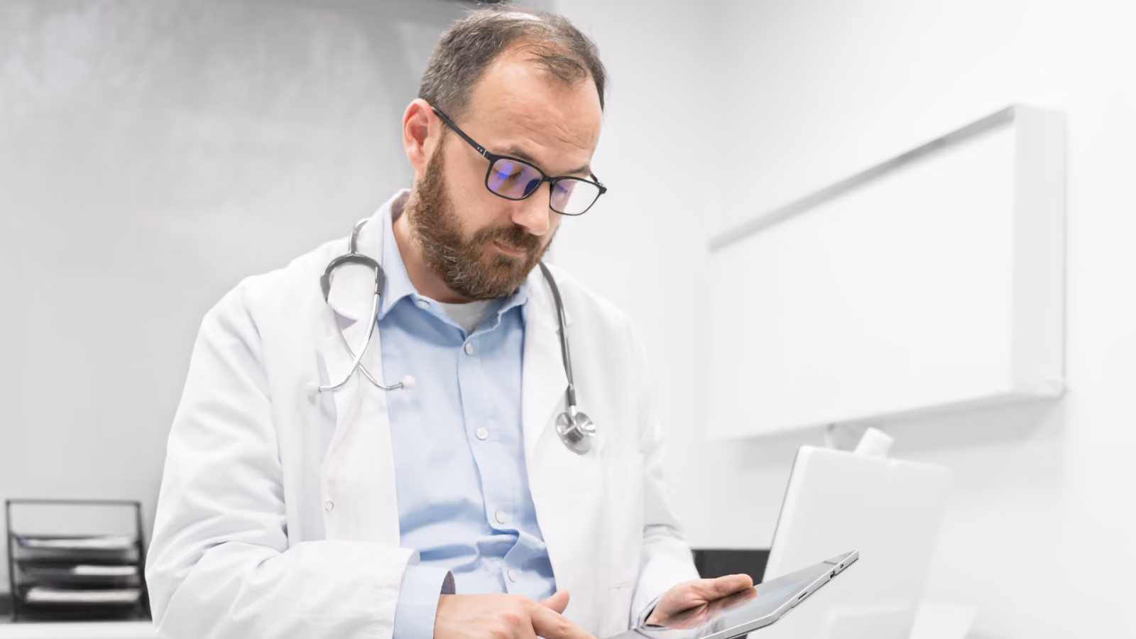 A doctor reviews labor cost data on a tablet to understand what labor cost management includes beyond wages.
