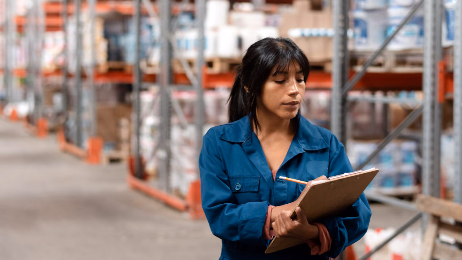 A warehouse worker tracks labor cost metrics on a clipboard to help calculate labor cost and spot cost drift.