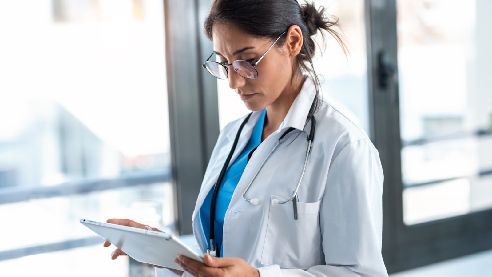 A medical professional uses a tablet to support a workforce management strategy with real-time scheduling and staffing data.