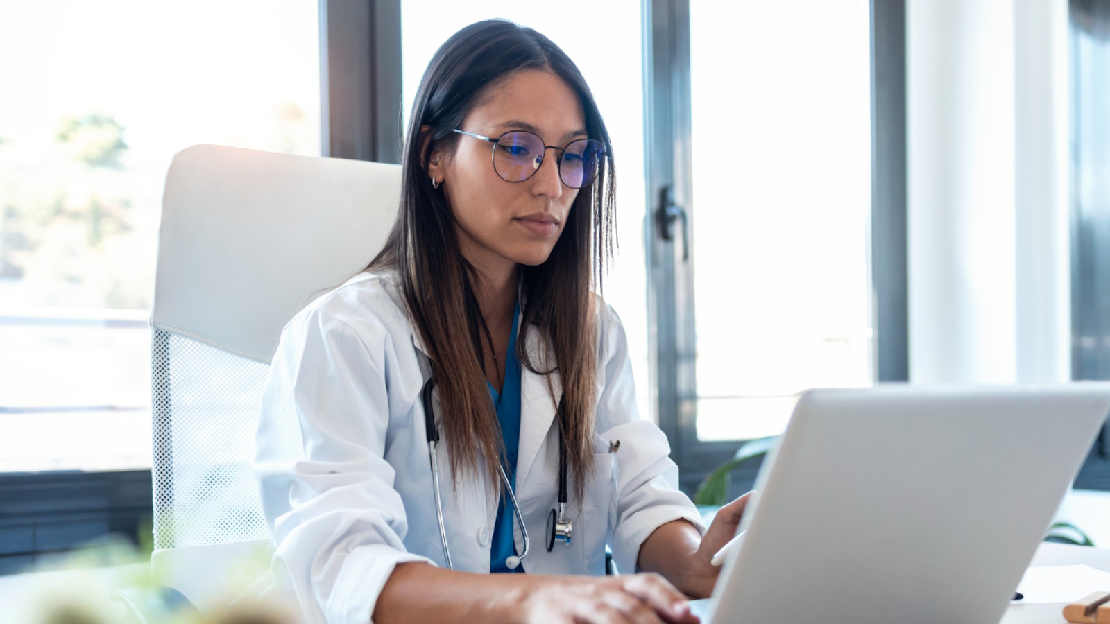 A doctor reviews workforce data on a computer while managing the workforce through weekly reviews and approvals.