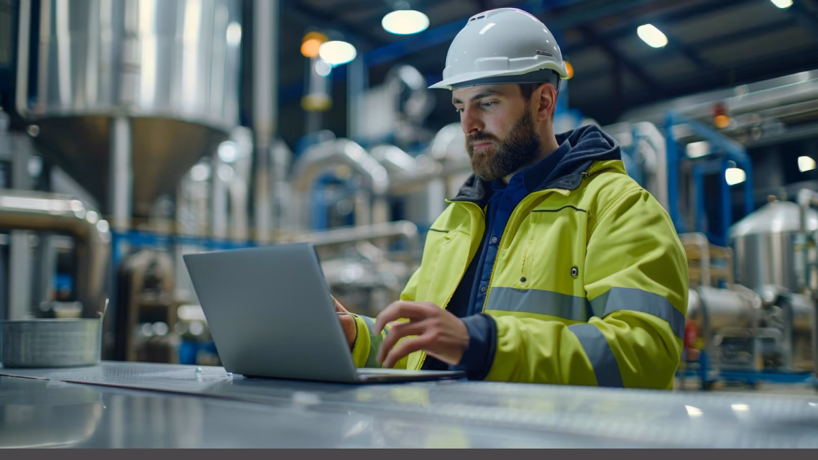  An engineer uses a laptop in an industrial setting to apply effective workforce management across multiple locations.