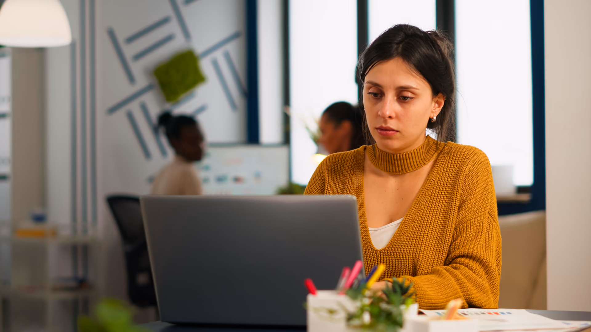 A woman working on her laptop, analyzing data related to workforce management metrics.
