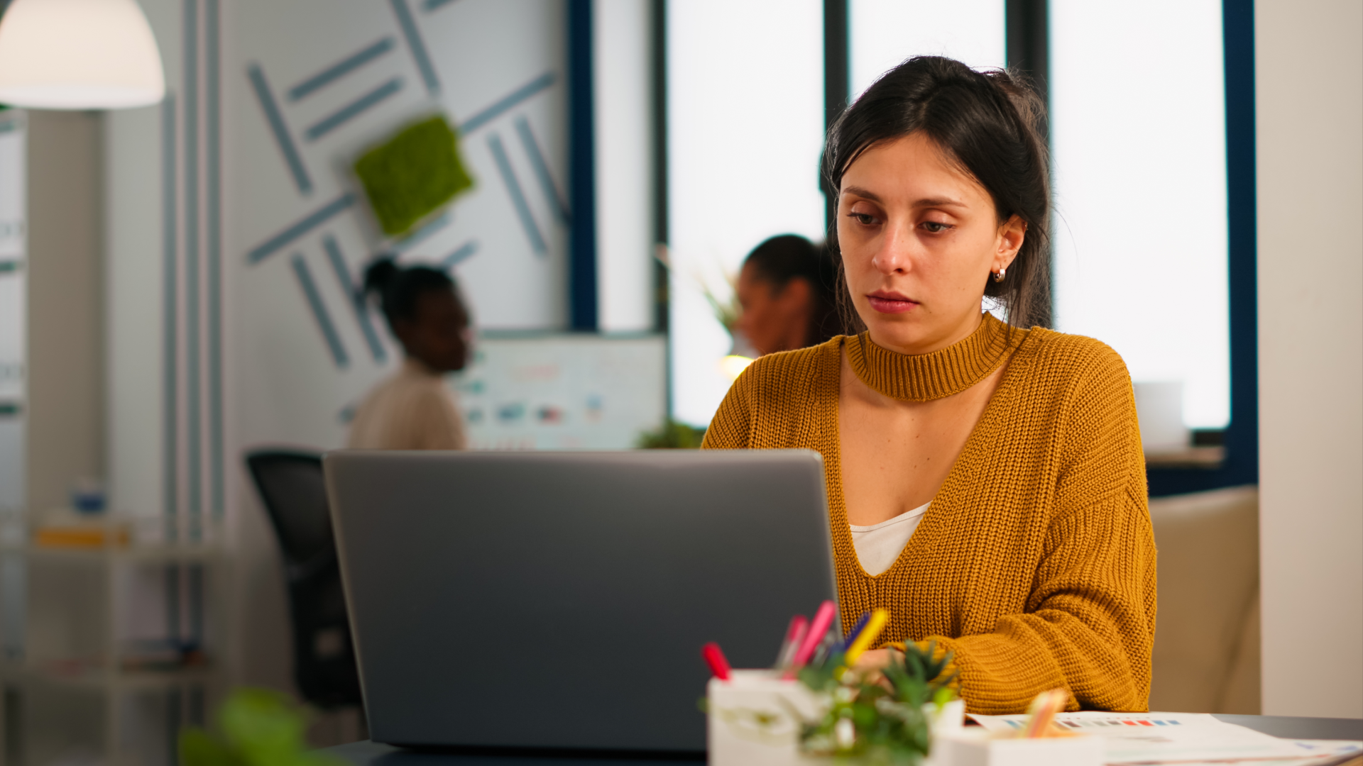 A woman working on her laptop, analyzing data related to workforce management metrics.