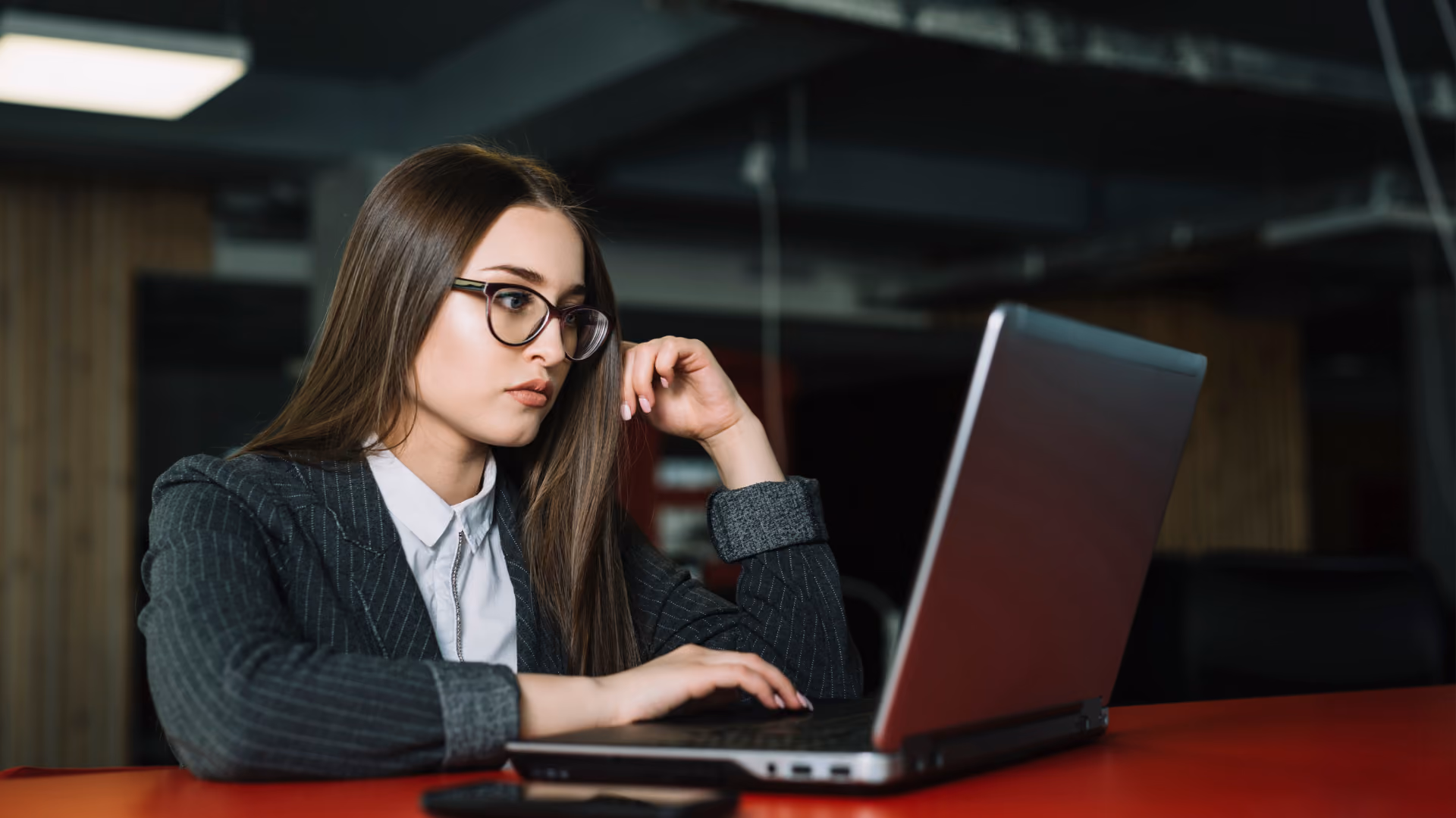 A woman in glasses intently reviewing a laptop to help build a shift swap policy.