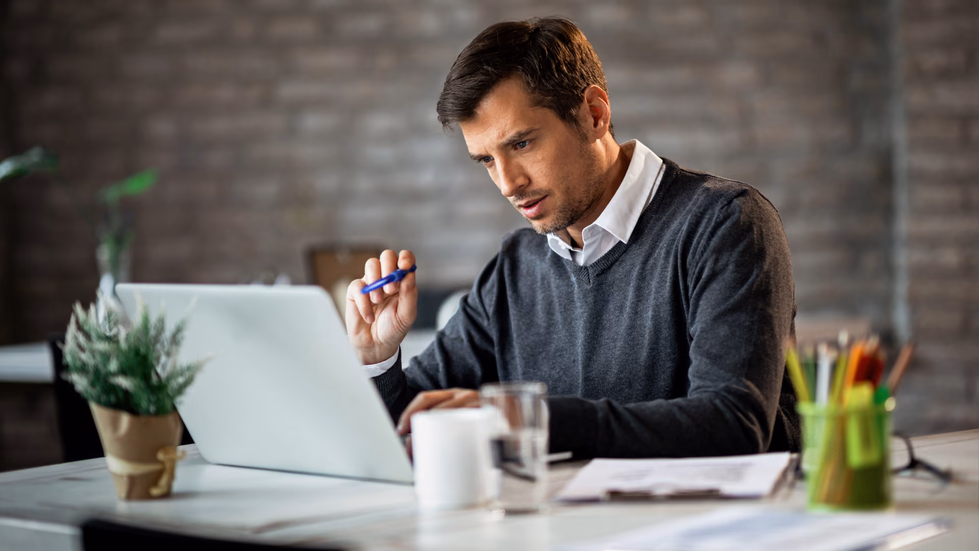 A focused man using a laptop and pen, managing the process from swap approval to payroll.