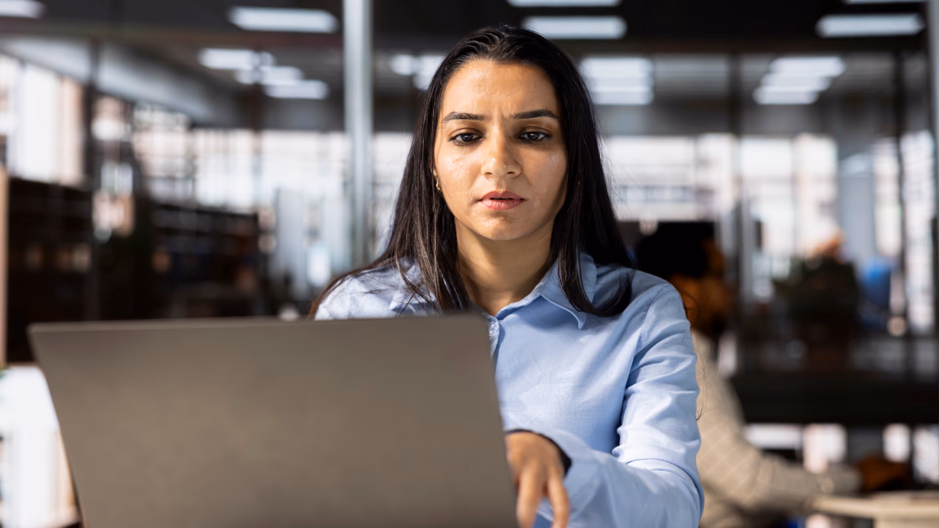 A woman focuses intently on her laptop, illustrating how to manage 10 common scheduling issues at work.